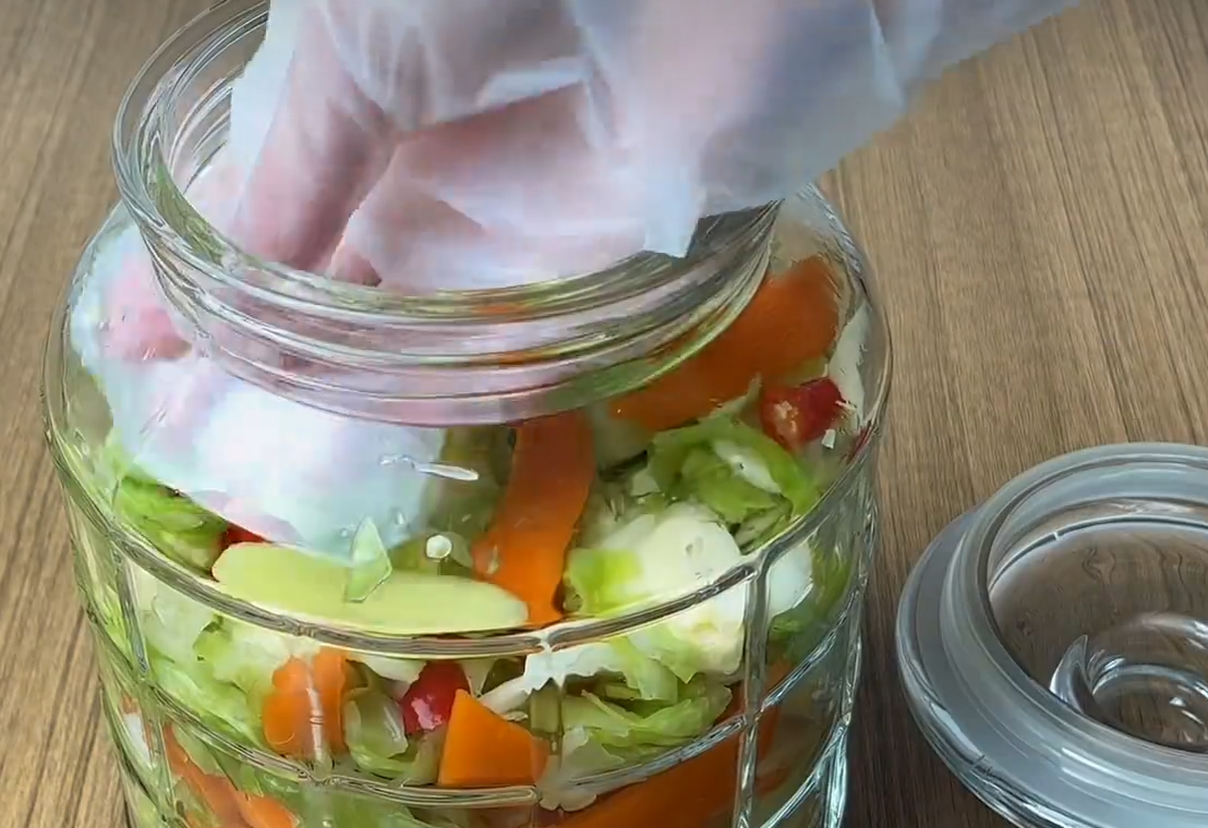 Pack cabbage mixture tightly into clean, dry glass container. Ensure it's oil and water free.