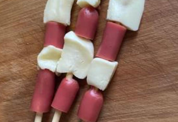 Instructions to prepare hot dogs by cutting them into smaller pieces and skewering with cheese.