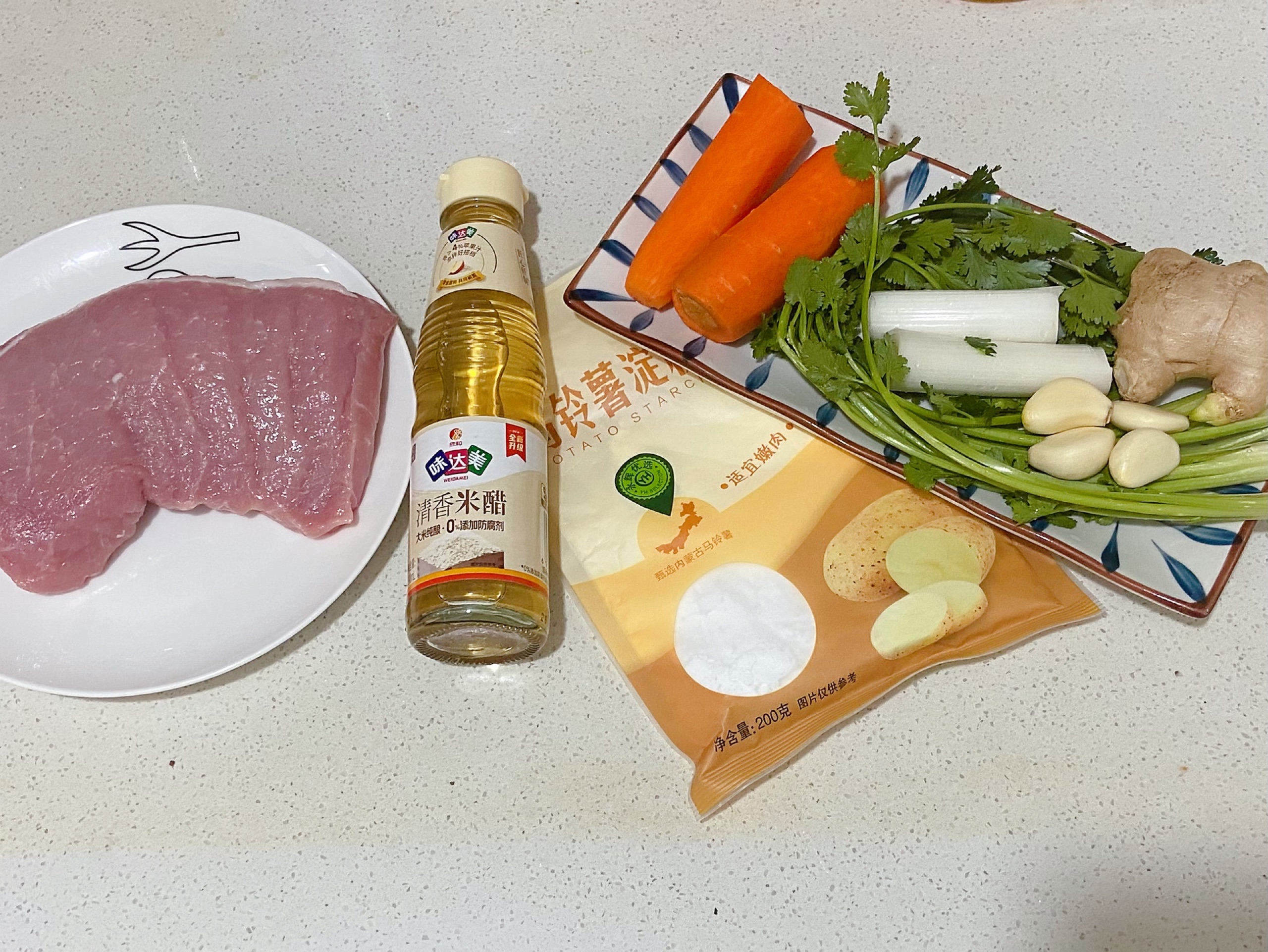 Gather ingredients for pork tenderloin dish: rice vinegar, potato starch, carrot, cilantro, ginger, garlic, sugar, soy sauce, etc.