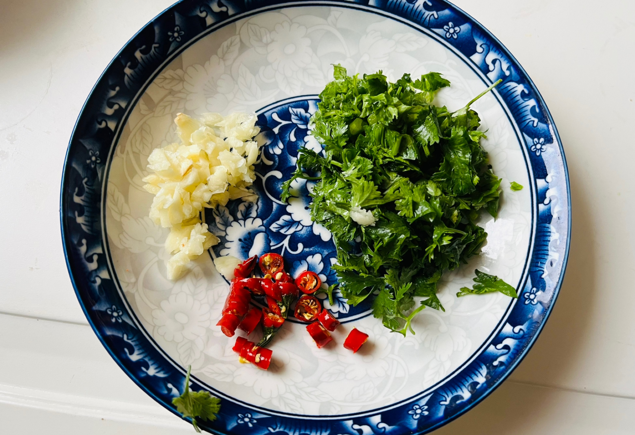 Chop garlic, chili pepper, small chili peppers, and cilantro sprigs.