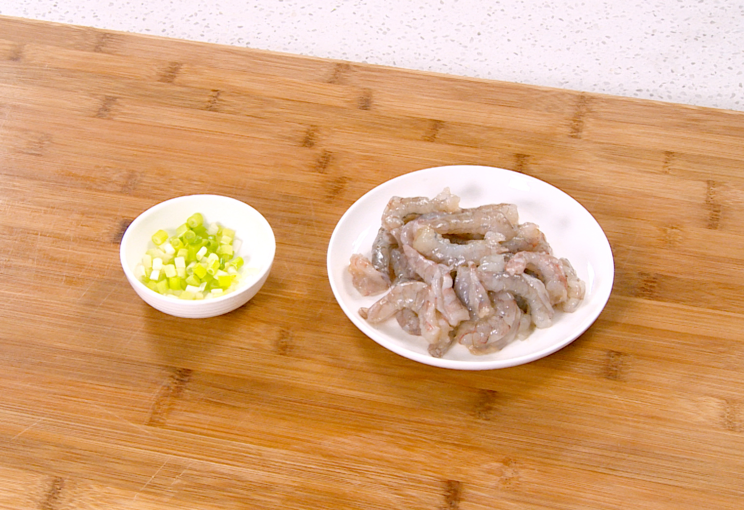 Chop green onion and prepare shrimp by deveining and butterflying.