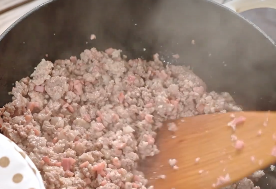 Cook ground beef and pork in a pan until moisture evaporates.