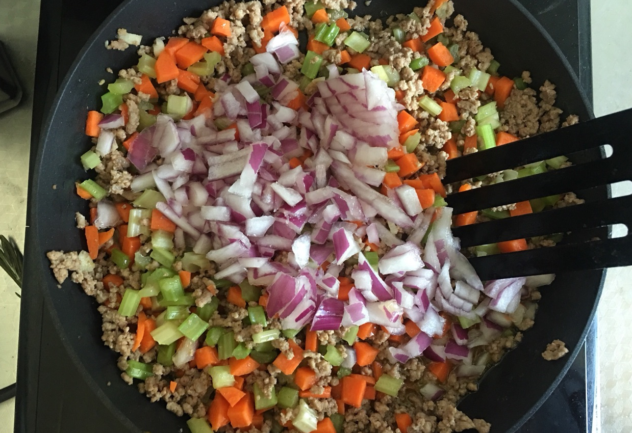 Add minced garlic, diced carrot, celery, and onion to pan, combine.