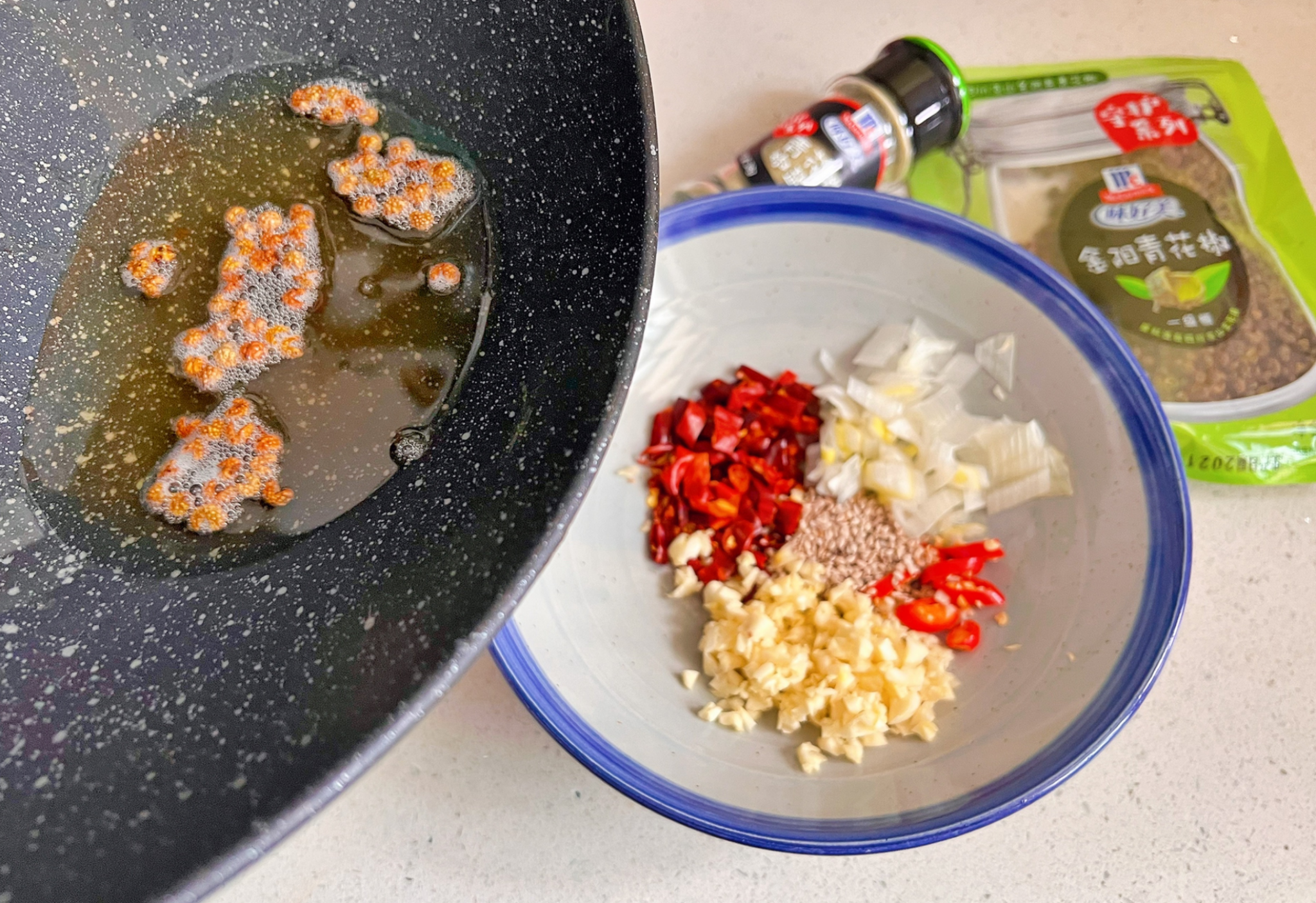 Adding fragrant oil & green Sichuan peppercorns to spices. Expect intense aroma of garlic, chili peppers & scallions.