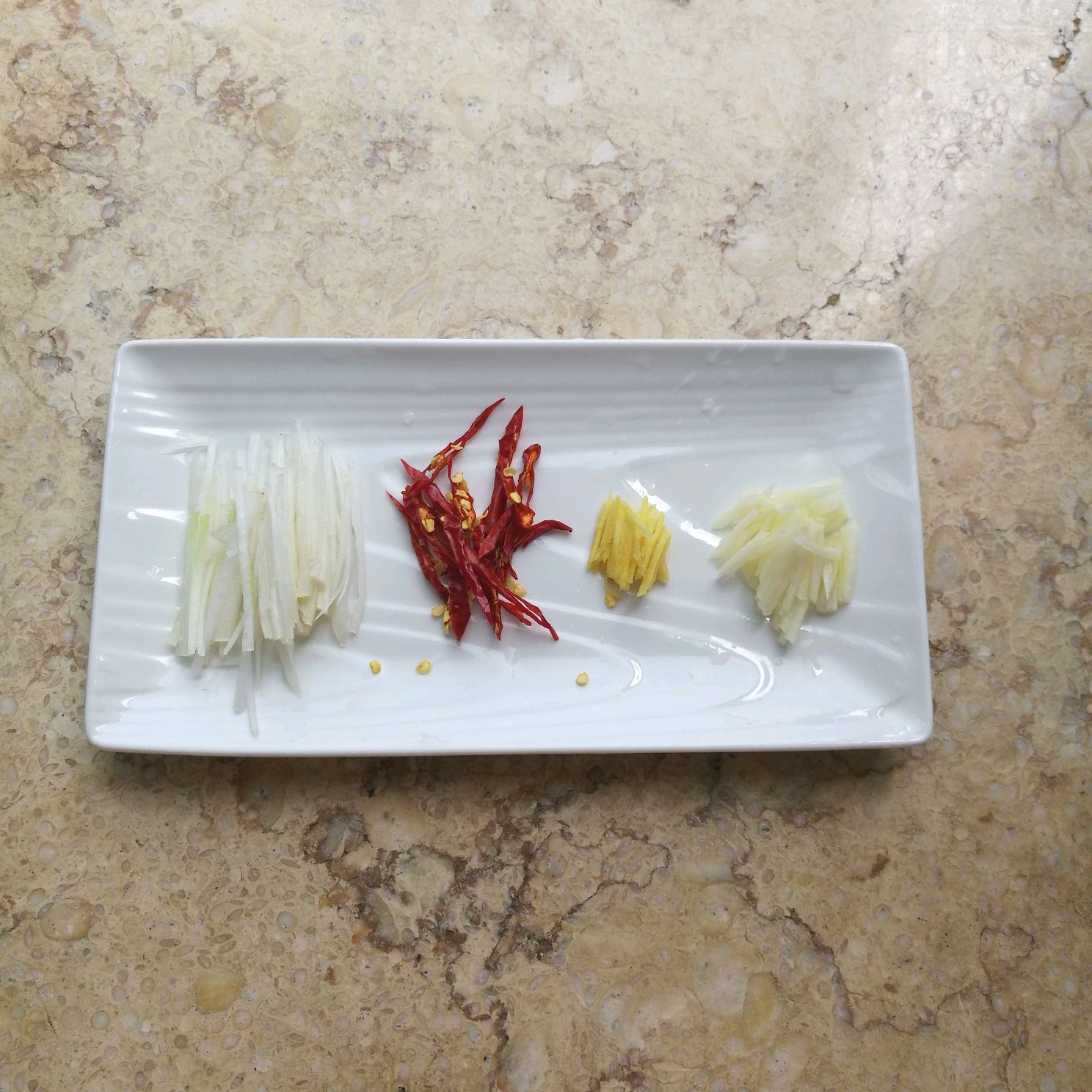 Prepare ingredients for the dish: slice ginger, garlic, scallion, and chili peppers into thin strips.