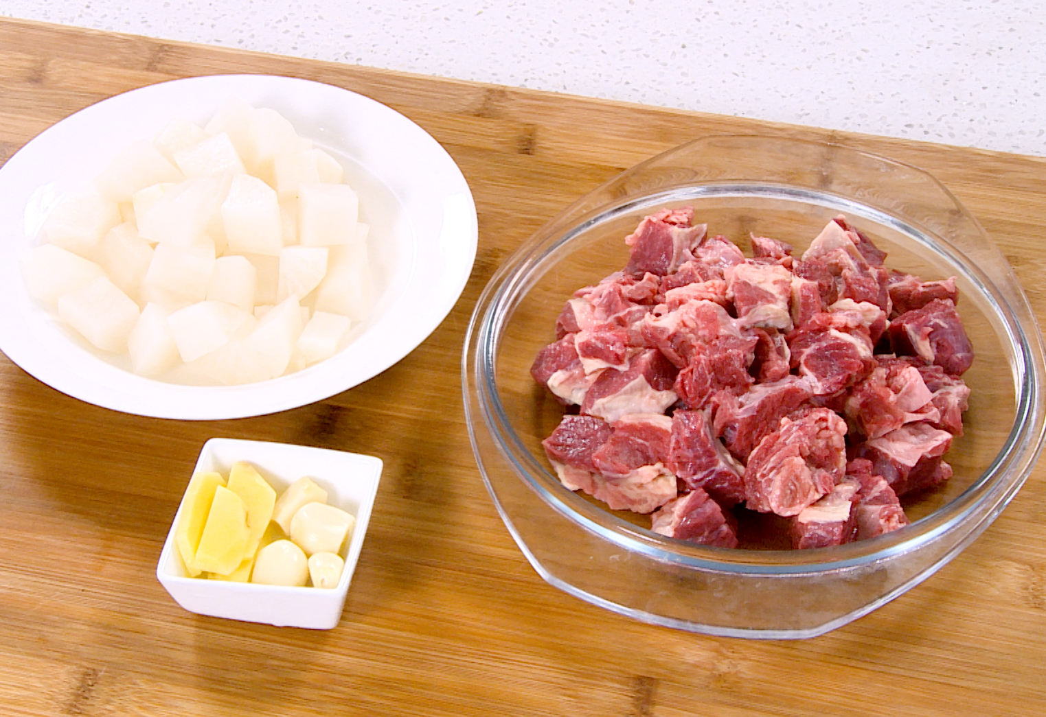 Prepare beef brisket, daikon radish, ginger, and garlic for cooking.